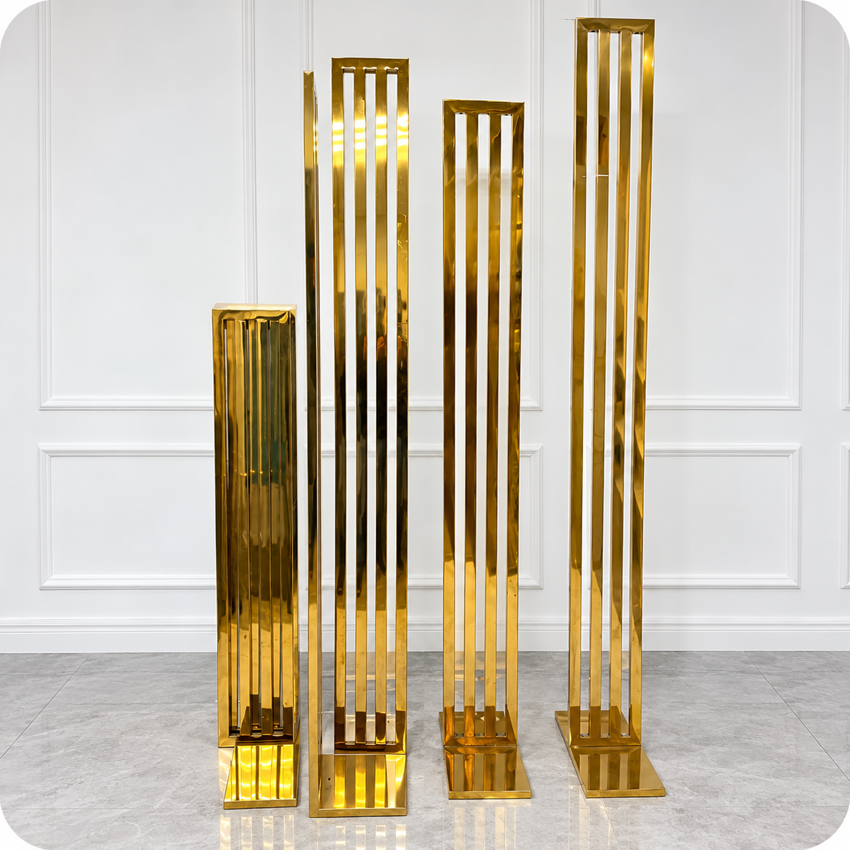 Disassembled gold metal wedding arch backdrop frames with vertical bars and rectangular bases, showing the rental structures in a compact storage arrangement at Rent Ottawa Decor.
