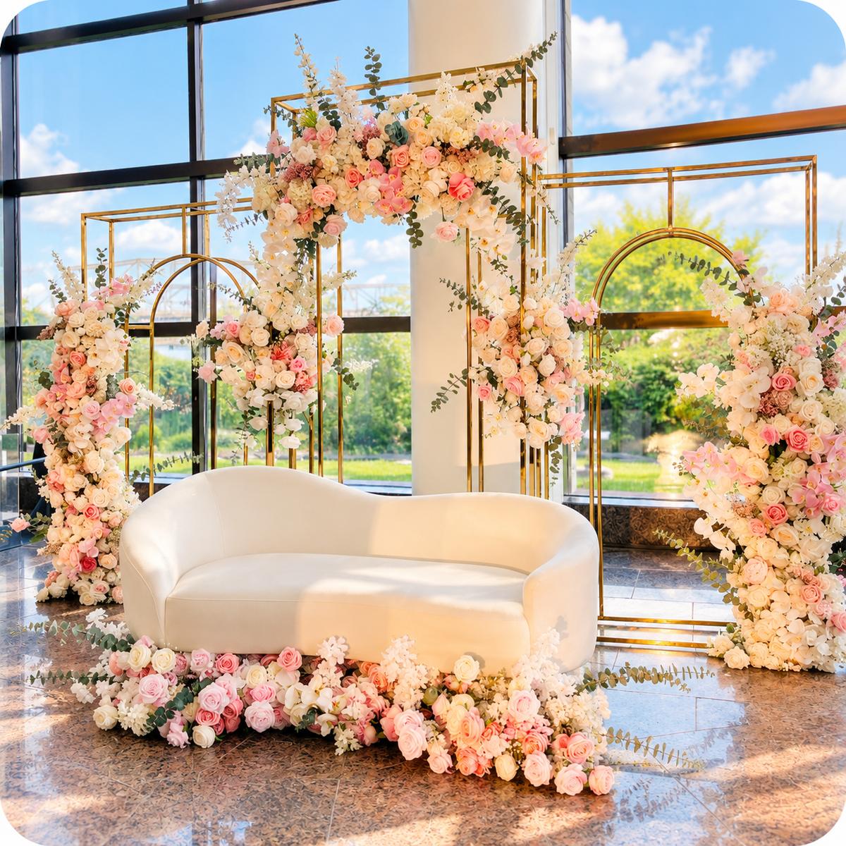 Elegant wedding lounge setup with gold geometric arch backdrops, pink and white floral arrangements, and a curved white sofa in Ottawa.